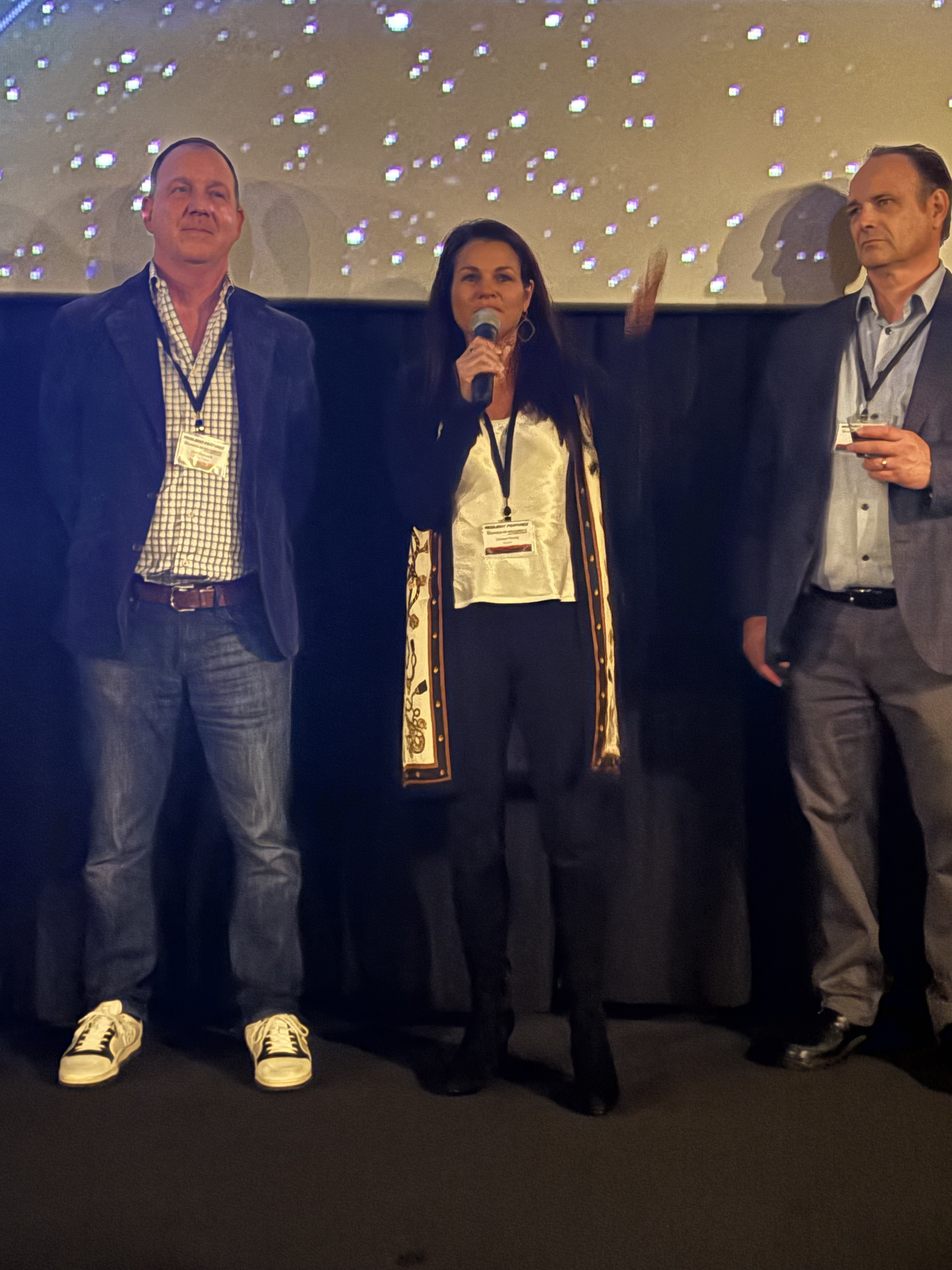 Sponsors speak on stage under the globe screen